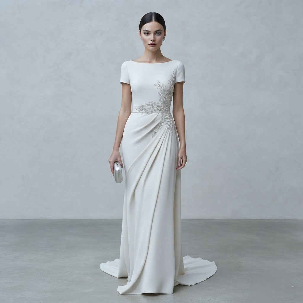 Vestido de novia minimalista de manga corta y escote barco con detalles de pedrería bordada en el lateral y silueta fluida de la Colección Mara.