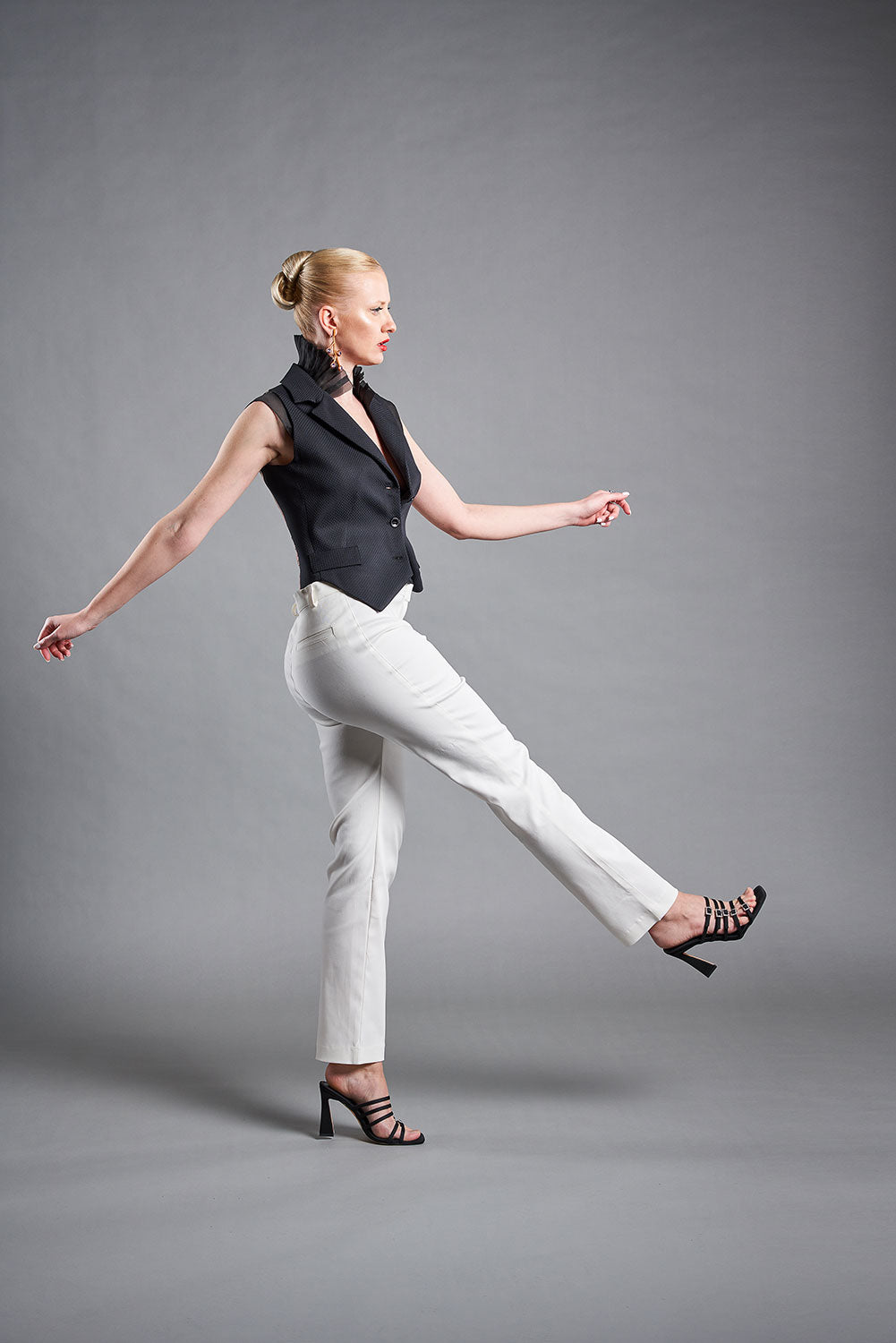 Modelo llevando chaleco negro con pantalón vaquero blanco y debajo un pechero de organza negro con cuello tablones. Colección medici queen de masum karimi