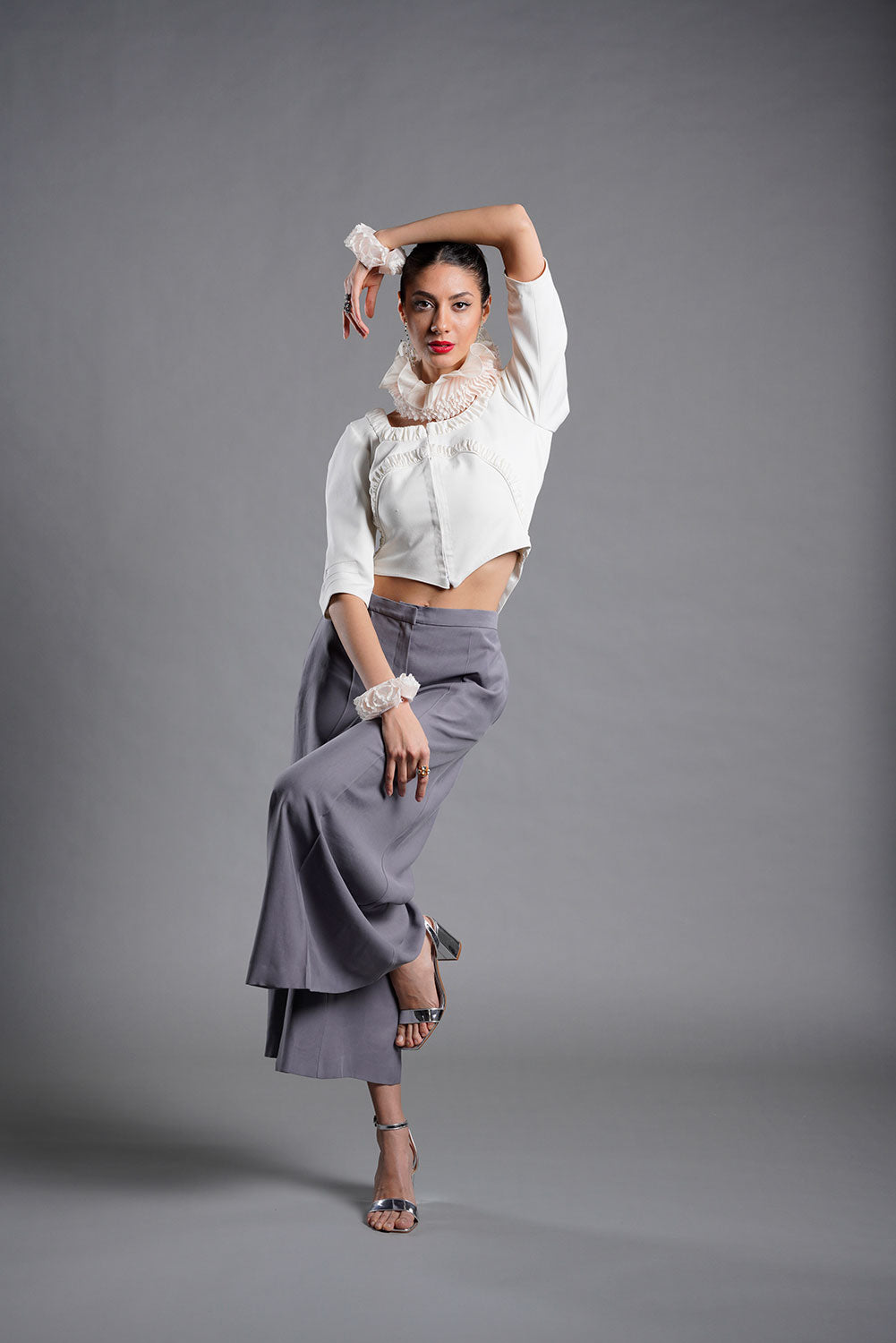 modelo luciendo chaqueta bolero blanco con pantalón ancho gris y golas de cuello y de puño blanco.  Colección medici queen de masum karimi