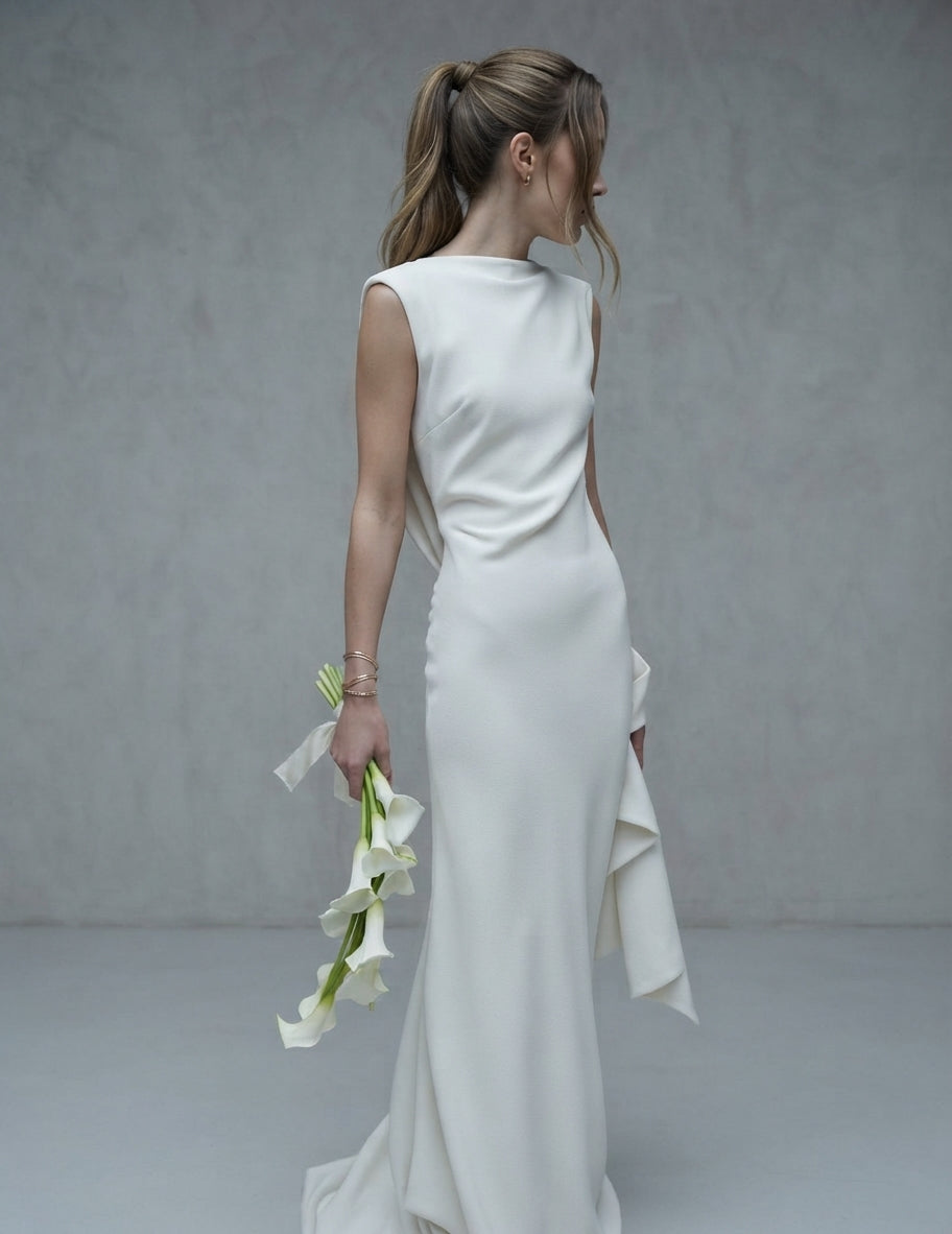 Vestido largo de novia sin mangas con cuello barco, cuerpo ligeramente drapeado y detalle de volantes laterales de la Colección Alma - Boda Civil.