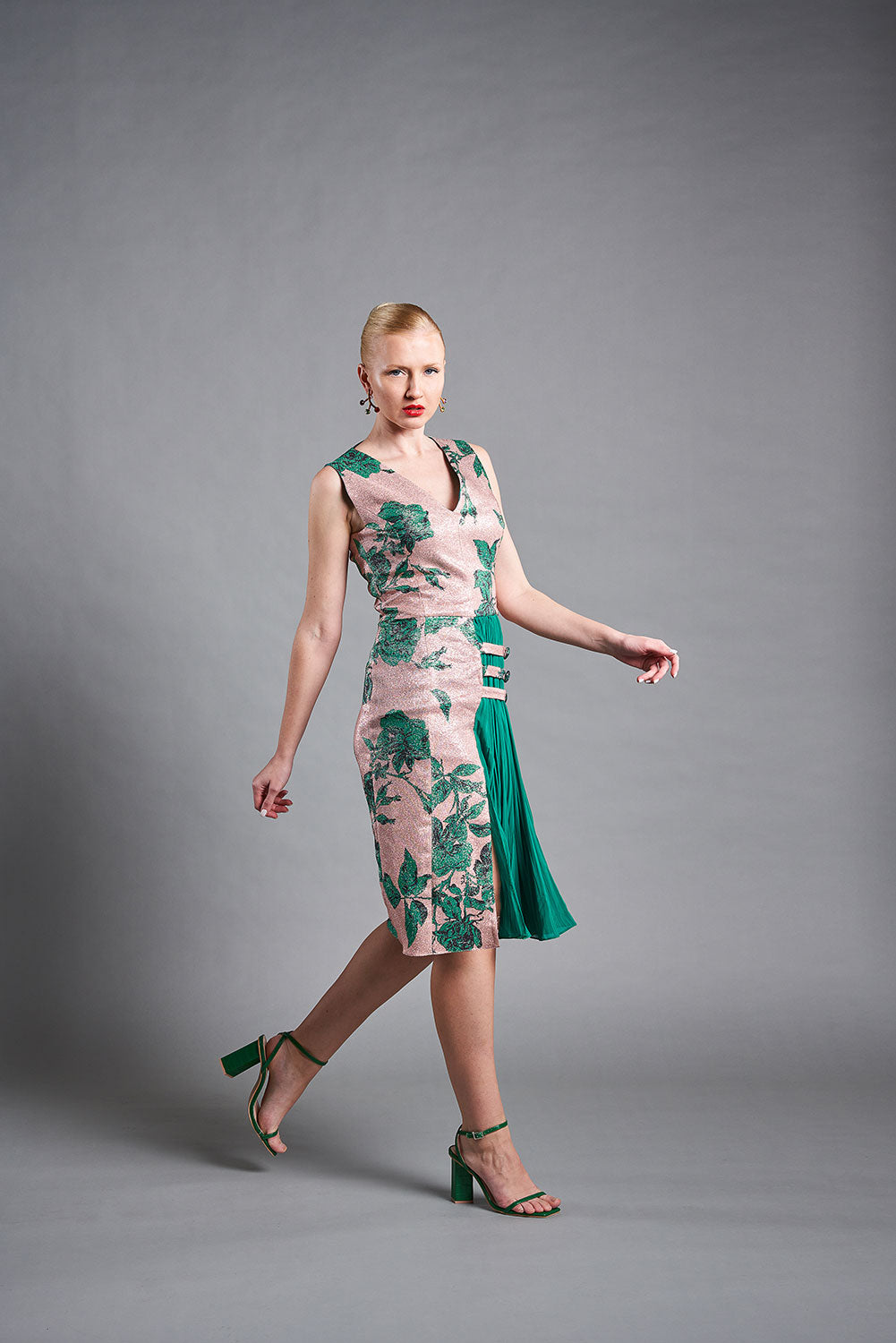 modelo posando con vestido cuello v, de corte midi y abertura delantera con goergette plisado.  Colección medici queen de masum karimi